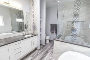 light bathroom design with glass shower, white bathtub, and dark counter