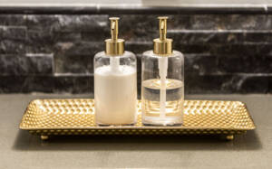 soap and lotion dispensers on gold plat with stone wall